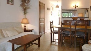 A cozy living room with a wooden table, a sofa, and a dining area with chairs and a table.