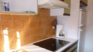 A compact kitchen with a sink, a coffee maker, and a refrigerator.