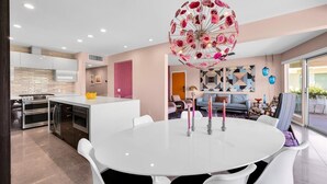 A modern kitchen with white cabinets, a central island, and a dining area with a white table and chairs. - A Design-Forward Midcentury Residence in Central Palm Springs! (Palm Springs)
