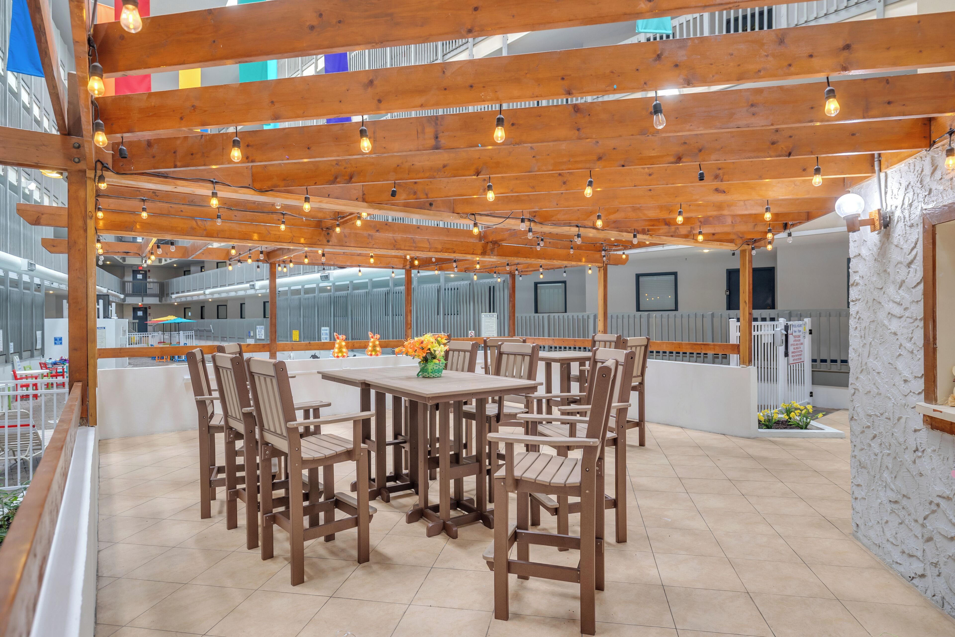 Une terrasse extérieure avec des tables et des chaises en bois, des guirlandes lumineuses et une vue sur le paysage urbain.
