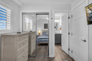 A hotel room with a sliding door leading to a balcony, a wicker dresser, a bed with a striped bedspread, and a mounted television displaying a welcome message. - Direct OCEANFRONT 1st floor End Unit Myrtle Beach Resort (Myrtle Beach)