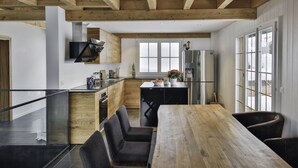 Une cuisine moderne avec des poutres en bois, une grande table à manger et une vue sur l’extérieur.