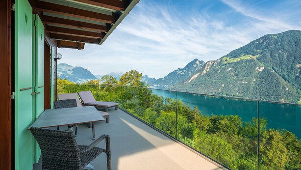 Un balcon avec une table et des chaises donnant sur un lac et des montagnes.