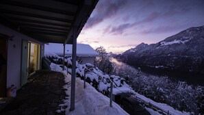 Un paysage enneigé offrant une vue sur des montagnes et un lac au crépuscule.