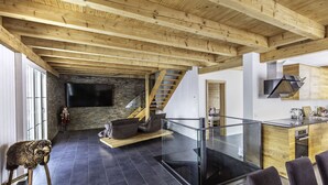 Un intérieur moderne avec un plafond en bois, une cheminée en pierre, un escalier et un coin cuisine.