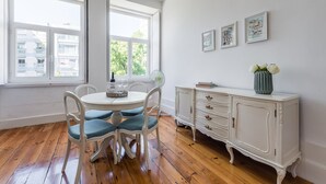 Un coin repas avec une table ronde, des chaises, un buffet blanc et des œuvres d’art accrochées au mur.