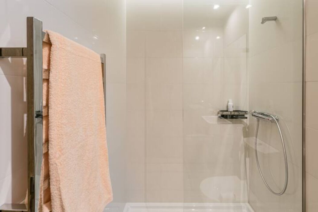 A modern bathroom with a glass shower enclosure, a towel rack, and a visible toilet.
