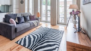 Ein modernes Wohnzimmer mit einem grauen Sofa, einem Teppich mit ZEBRA-Muster und einem Holzesstisch.