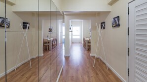 A hallway with mirrored walls, wooden flooring, and a dining area with tables and chairs. - GuestReady - October Tide (Porto)