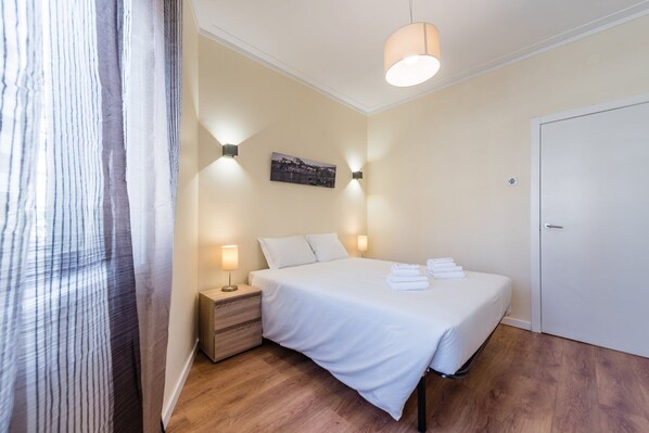 Une chambre d’hôtel avec un lit, des lampes de chevet, une table de chevet, une porte et une vue sur l’extérieur.