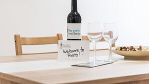 A table with a bottle of wine, two wine glasses, a welcome sign, and a bowl of nuts. - GuestReady - October Tide (Porto)