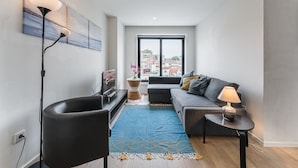 A modern living room with a sofa, a coffee table, a floor lamp, and a TV. - GuestReady - Cosy spot near Porto city centre (Porto)