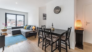 A modern living room with a sofa, dining table, chairs, a clock, and a lamp. - GuestReady - Cosy spot near Porto city centre (Porto)