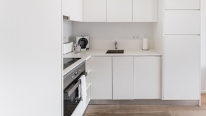 A modern kitchen with white cabinetry, a stainless steel sink, a coffee maker, and a toaster. - GuestReady - Cosy spot near Porto city centre (Porto)