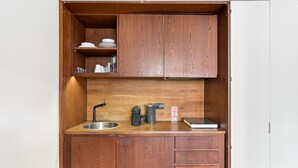 A compact kitchen with wooden cabinetry, a stainless steel sink, and a coffee machine. - GuestReady - Rivoli Studio (Porto)