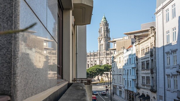 A view of a street with historic buildings and a prominent clock tower in the background.