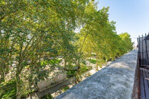 Ein Baumweg, eine Betonmauer und ein Metallzaun.