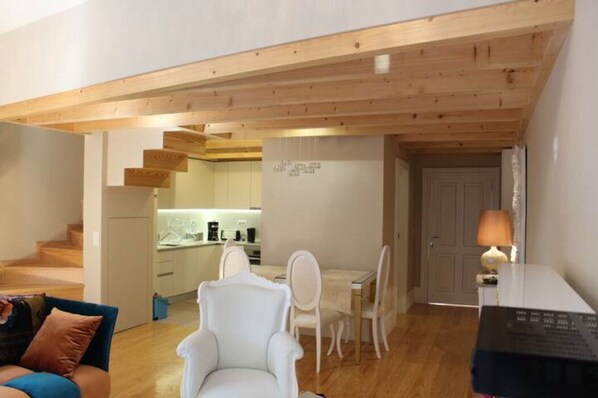 A modern apartment with a dining area, kitchen, and a staircase leading to an upper floor.