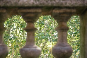 A stone balustrade with a view of a leafy tree through the gaps.