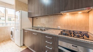 A modern kitchen with dark wood cabinets, a stainless steel sink, a built-in gas stove, and a built-in washing machine.