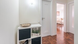 A hallway with a white door, a basket on a shelf, and a potted plant.
