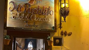 The entrance to Mi Pueblo Hotel Posada in Jalisco, featuring a welcoming sign and a well-lit interior with potted plants and a chandelier. -  Hotel Mi Pueblito Tapalpa (Tapalpa)