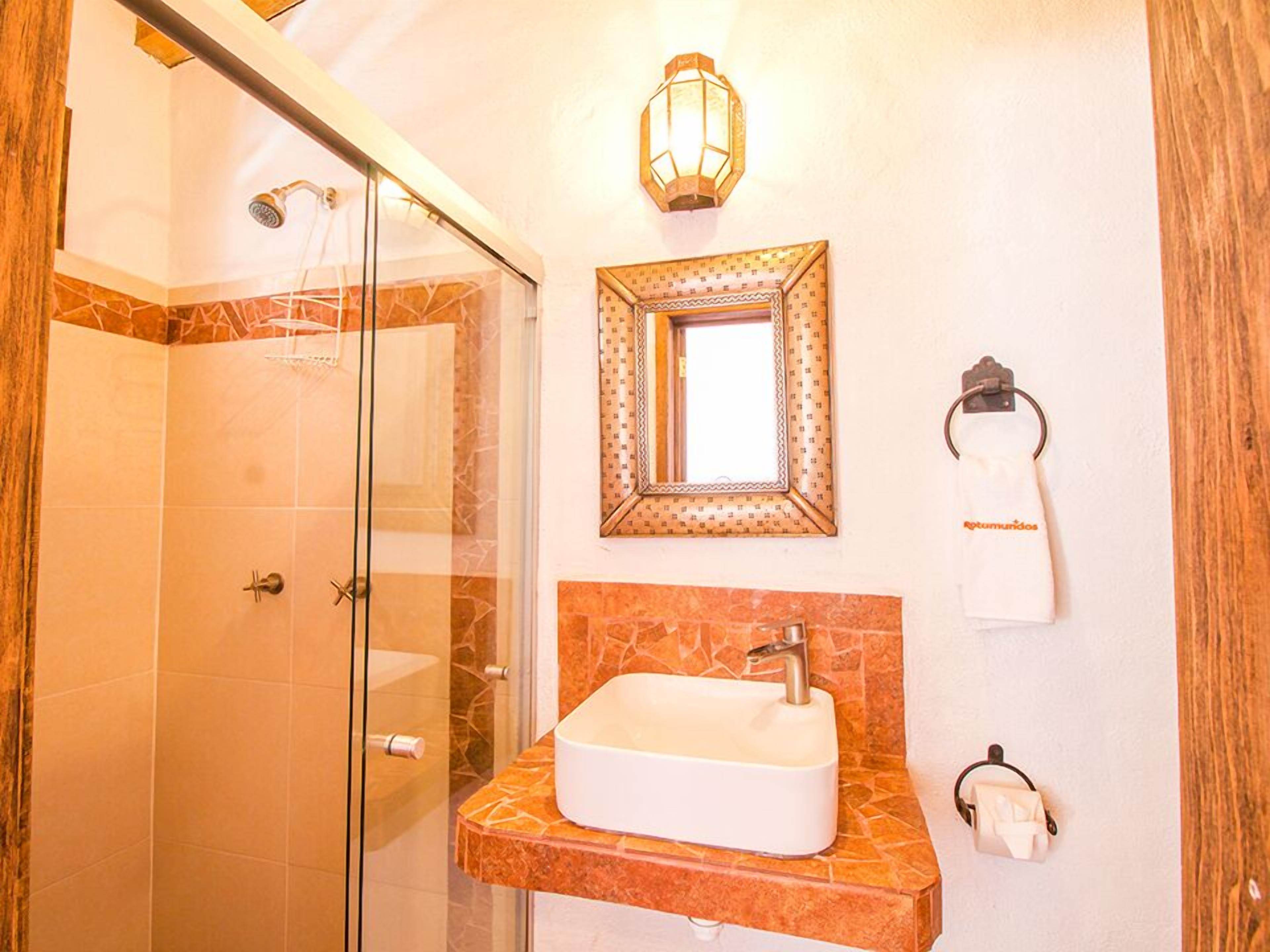 A bathroom with a glass shower enclosure, a sink with a marble countertop, a wall-mounted mirror, and a towel rack with a towel.