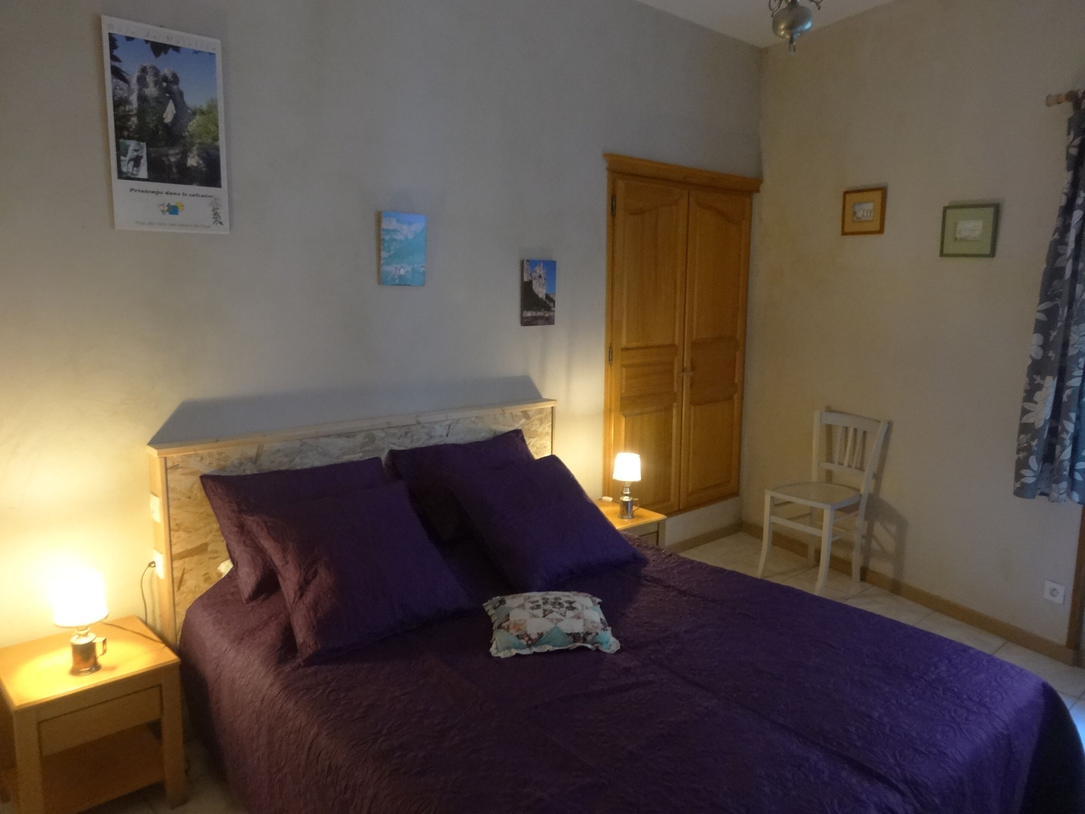 A bedroom with a bed, nightstands, a chair, and a wardrobe.