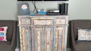Eine rustikale Holzkabine mit Schubladen und Türen, ein flachbildfernseher darüber angebracht und zwei graue Sofas mit dekorativen Kissen.