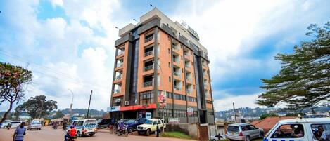A multi-story building with balconies, a commercial ground floor, and a clear view of the sky.