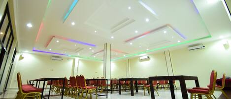 A conference room with a white ceiling, red chairs, and a black table.