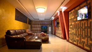 Un salon moderne avec un canapé en cuir, un téléviseur à écran plat et un mur orné d’un motif.