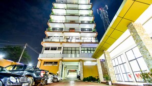 Un hôtel à plusieurs étages au design moderne, doté de balcons à chaque étage, de grandes fenêtres et d’une entrée bien éclairée.