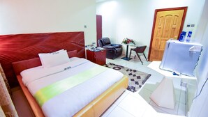 Une chambre d’hôtel avec un lit, un bureau, une chaise, une télévision et une porte.
