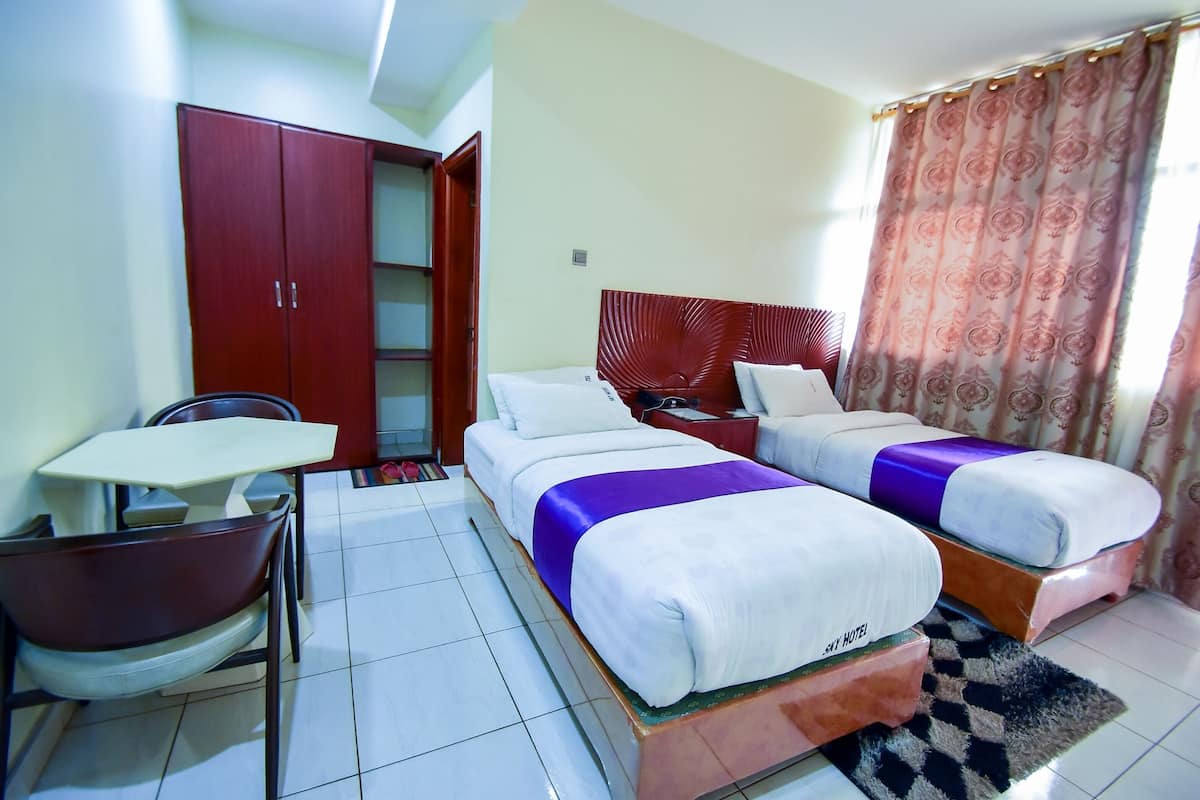 Une chambre d’hôtel avec deux lits, un bureau, une chaise, une armoire et une salle de bain.