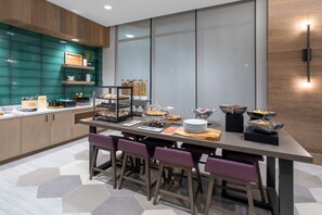 A modern kitchen with a breakfast bar, wooden cabinets, and a large window. - Hilton Garden Inn Albuquerque Downtown (Albuquerque)