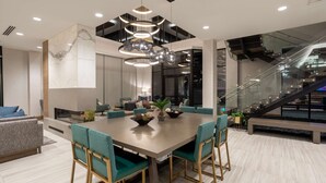 A modern dining area with a large table, green upholstered chairs, and a unique chandelier. - Hilton Garden Inn Albuquerque Downtown (Albuquerque)
