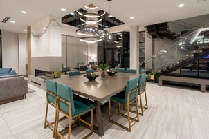 Un comedor moderno con una mesa grande, sillas tapizadas en verde y una lámpara colgante original.
