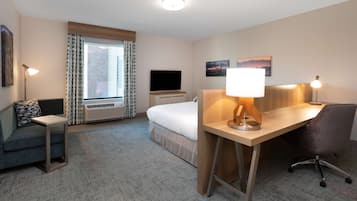 A hotel room with a bed, a desk, a chair, a television, and a window with curtains.