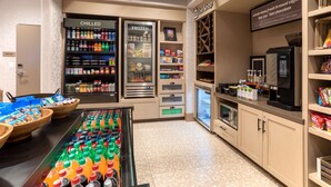 A self-service beverage station with chilled and frozen drink options, a coffee machine, and a refrigerated display case. - Hilton Garden Inn Albuquerque Downtown (Albuquerque)