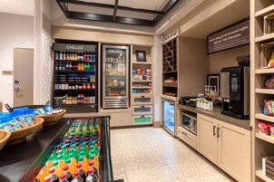 Una estación de autoservicio para bebidas con opciones de bebidas frías y congeladas, una máquina de café y un refrigerador.