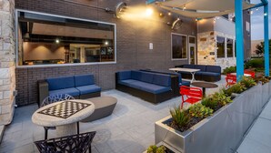 Un espace extérieur aménagé avec des canapés bleus, une table ronde et des chaises rouges.