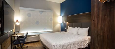 A hotel room with a bed, desk, chair, TV, and a large window with a view.