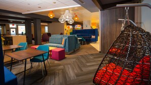 Un espace de détente moderne, doté de sièges, de tables et d’un fauteuil suspendu.