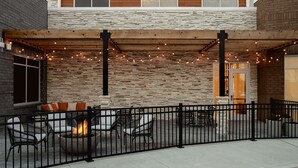 Un patio al aire libre con una chimenea, asientos e iluminación colgante.