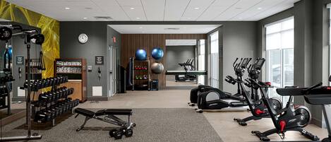 Un gimnasio con diversos equipos de ejercicio, incluyendo cintas de correr, bicicletas estáticas y pesas libres.