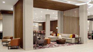 En modern hotellobby med en sittgrupp, ett område för måltider och en receptionsdisk.