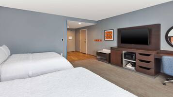 Habitación de hotel con dos camas, televisión, escritorio con cajones y microondas.