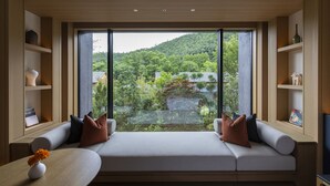 A modern room with a large window, a built-in sofa, and wooden shelves.