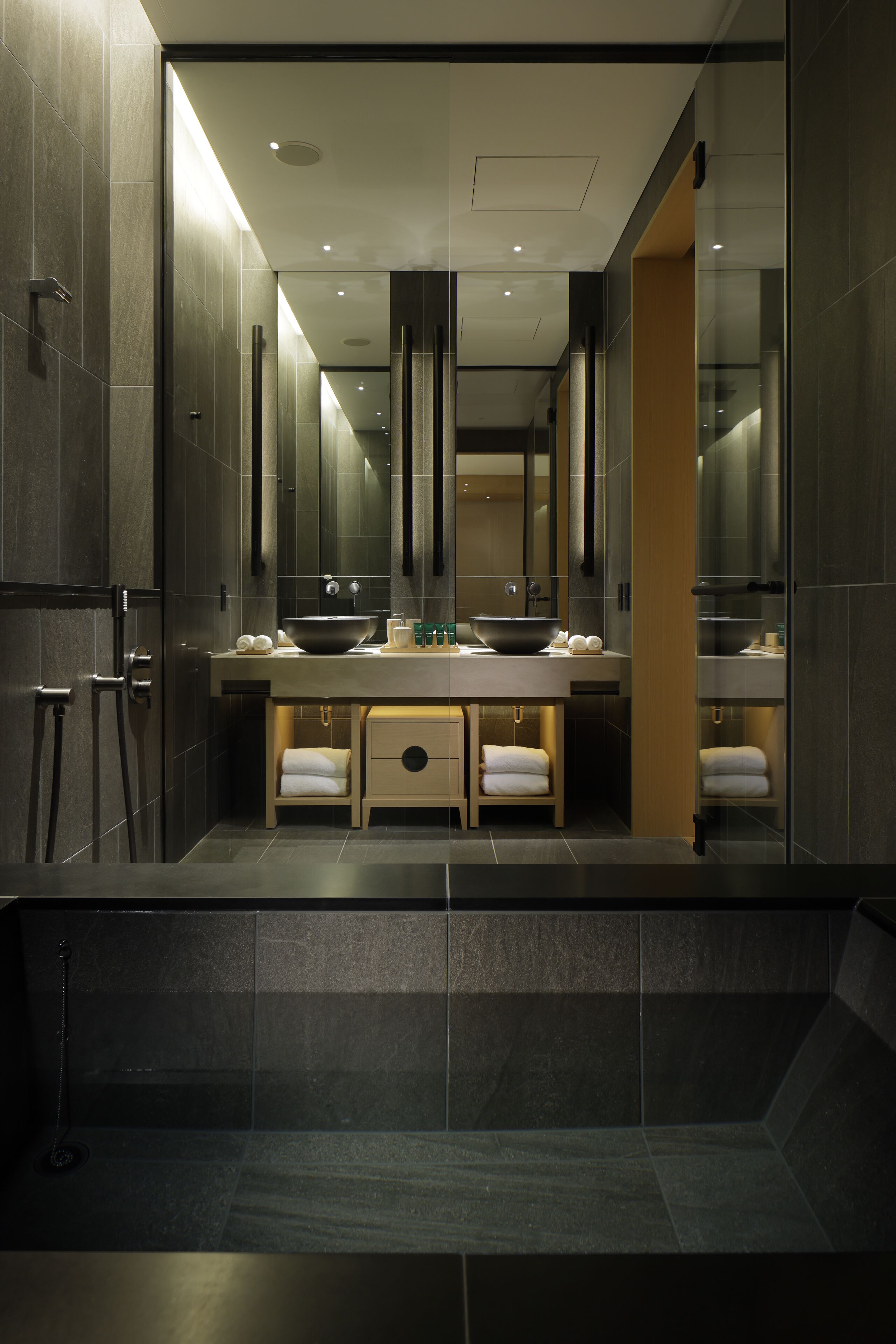 Un baño moderno con un espejo grande, dos lavamanos y una bañera.